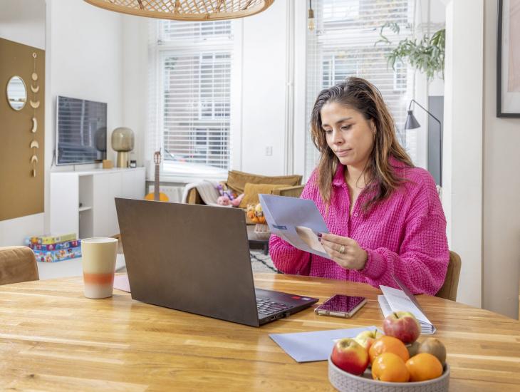 Een vrouw zit achter haar laptop en regelt haar belastingzaken online.