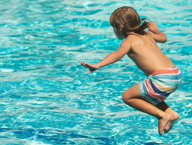 Klein kind springt in een zwembad